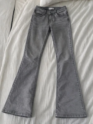 Grå bootcut jeans från Perfect Jeans - Säljer ett par grå bootcut jeans från Perfect Jeans i storlek 36. Jeansen har klassisk femficksmodell, hög midja och utsvängda ben. Har en pytteliten fläck som ni kan se på sista bilden.