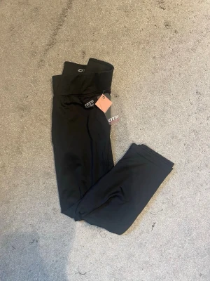 Svarta leggings från OTP - Snygga svarta leggings från OTP med hög midja och stretchigt material. Perfekta för träning eller chill, med diskret logga framtill i vitt. Mjuka och följsamma för maximal komfort. Lappen sitter kvar.