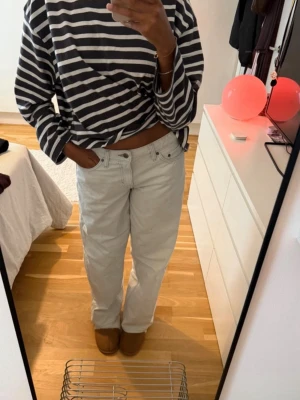 Vita raka jeans - Säljer ett par vita jeans med rak passform och klassisk femficksdesign Storleken är W28 L34. Jeansen har bälteshällor och silverfärgade nitar. Perfekta för en avslappnad och trendig look. Materialet är denim i bomull.