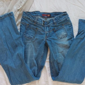 Blå bootcut jeans från Element - Säljer ett par blå bootcut jeans från Element med snygga slitningar och kontrastsömmar. Jeansen har fem fickor, bälteshällor och klassisk knappgylf. Tillverkade i denim med en cool tvättad look som passar perfekt till en avslappnad stil. Innerbensläng:77 Midjemått: 36/37