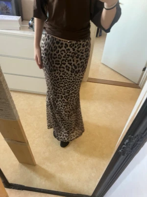 Leopardmönstrad långkjol - Säljer en snygg långkjol med leopardmönster. Kjolen sitter tight sen svänger ner vid benen. Dubbel laced och perfekt till sommaren. Xs men passar även mig som S