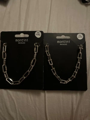 Silverfärgat kedjehalsband Montini - Säljer två trendiga halsband från Montini i silverfärgad metall. Båda har chunky kedjelänkar med modern, kantig design. Perfekt accessoar för att lyfta din outfit med en edgy touch. Säljes styckvis eller tillsammans. Säljer 1 för 129kr och 2 för 260kr