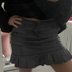 Grå volangkjol med fickor - Säljer en grå/lila kortkjol med volangkant och markerade sömmar. Storlek 34 men skulle säga att det mer är som en 36!