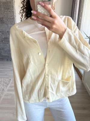 Ljusgul/ beige  kofta med ficka - Säljer en ljusgul/ beige kofta med knappar framtill och en liten ficka på ena sidan. 💕