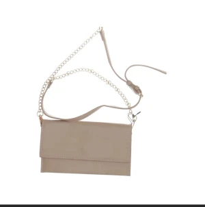 Beige kuvertväska från Åhléns - Stilren beige kuvertväska från Åhléns i slätt skinn med justerbar axelrem och snygg kedjedetalj. Enkel design med lock och raka linjer, perfekt för dig som gillar minimalistisk stil. Väskan har en neutral färg som passar till många outfits.