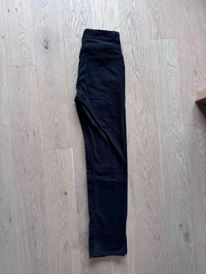 Svarta slim fit jeans från Dressmann, oanvända! - Oanvända! Svarta jeans i slim fit-modell från Dressmann. Klassisk femficksdesign och smal passform som sitter snyggt längs benen. Perfekta för dig som gillar en stilren och enkel look. Materialet är mjukt och följsamt för extra komfort. W39 L33