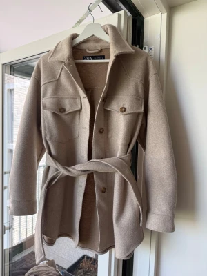 Kappa från zara  - 🤍 Zara kappa/jacka i beige 🤍 Säljer denna superfina och trendiga jacka från Zara i storlek M.  fint skick och perfekt  till våren/hösten 🍂✨ Knytbälte medföljer och jackan är både stilren och lätt att matcha.