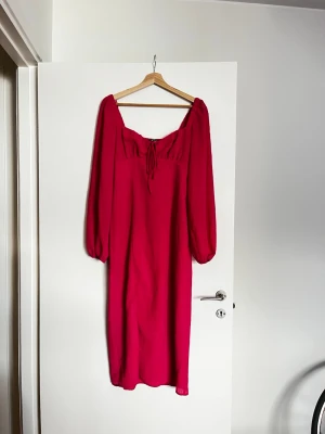 Rosa långklänning med snörning - En snygg rosa långklänning med puffiga långärmar och snörning framtill vid bysten. Använd 1 gång, från Gina.