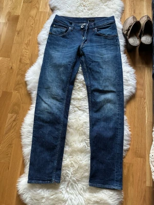 Tiger of Sweden Mörkblå raka jeans - Snygga mörkblå jeans med rak passform och klassisk femficksdesign. Jeansen har en lätt tvättad look med subtila slitningar framtill och bakfickor. Perfekta för en avslappnad och stilren outfit.