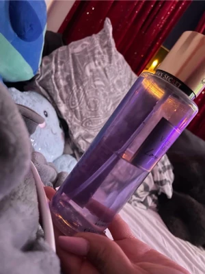 Victoria's Secret Love Spell mist - En snygg parfymmist från Victoria's Secret i doften Love Spell. Flaskan är genomskinlig med lila vätska och har ett guldigt lock. Perfekt för dig som gillar fruktiga och blommiga dofter. Flaskan är av plast och har en stilren design.