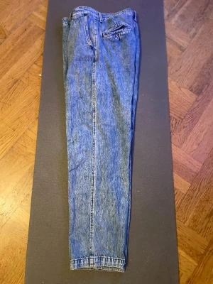 Levis XX chino - Ett par klassiska blå mom jeans med hög midja och raka ben. Jeansen har fem fickor och stängs med dragkedja och knapp. Perfekta för en avslappnad och trendig look. Tillverkade i denim.
