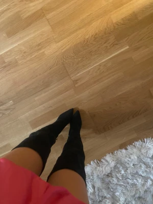 Svarta overknee stövlar i mockaimitation - Säljer ett par svarta overknee stövlar med spetsig tå och smal klack. Stövlarna är i mockaimitation och sitter tight längs benen för en snygg siluett. Perfekta att styla med klänning eller kjol för en trendig look.
