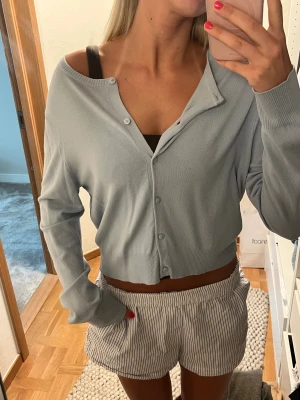 Ljusblå cropped cardigan - Säljer en ljusblå cropped cardigan med långa ärmar och knappar framtill från H&M. Tröjan har en avslappnad passform och är tillverkad i ett tunt, mjukt stickat material. Perfekt att styla över ett linne eller topp. Storlek L men skulle säga att den är mer en XS/S