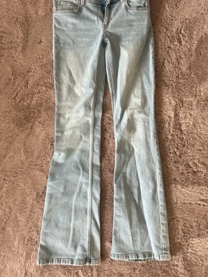 Ljusblå bootcut jeans - Säljer ett par ljusblå bootcut jeans med klassisk femficksdesign och utsvängda ben. Jeansen har normal midja och är tillverkade i denim med en snygg tvätt. 