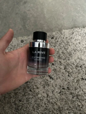 La Rive Extreme Story Eau de Toilette 50ml - Snygg parfymflaska från La Rive med namnet Extreme Story. Flaskan är cylindrisk med svart och silverfärgad design och har en svart kork. Perfekt för dig som gillar stilrena och moderna dofter. 50ml