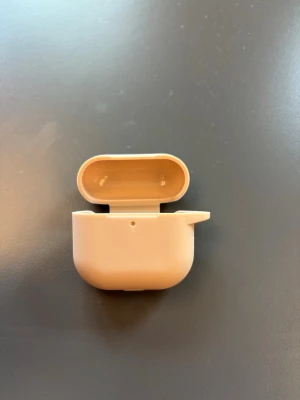 Beige silikonfodral till AirPods 4 - Snyggt och stilrent beige silikonfodral till AirPods. Fodralet har en mjuk och matt yta som skyddar mot repor och stötar. Passar perfekt runt laddningsetuiet och har öppning för laddningsport. Enkel att ta med och ger ett modernt intryck.
