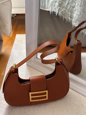 Brun väska  - Snygg väska i läder/skinn- material. Köpt i en märkesbutik på Kap Verde för 1499 svenska kronor. Dessvärre kommer den inte till den användning som jag önskar, men den är SUPERSNYGG. 