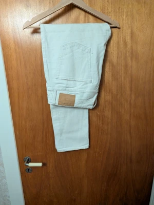 Vita jeans från Jack and Jones - Säljer ett par vita jeans från Jack and Jones med raka ben och klassisk femficksdesign. Jeansen har knäppning med knappar framtill och är tillverkade i bomull. Perfekta för dig som gillar en clean och stilren look.