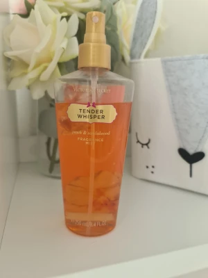 Victoria's Secret Tender Whisper mist - Fräsch doftmist från Victoria's Secret i doften Tender Whisper med inslag av persika och sandelträ. Flaskan är genomskinlig med orange vätska och har en guldfärgad spraypump. Perfekt för dig som gillar fruktiga och varma dofter.Säljer nu av min vintage kollektion. Perfekt för samlare. Eftersom dofterna är vintage kan lukten skilja sig markant från nya, och köps därmed på eget bevåg.