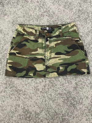 Kamouflage minikjol från Boohoo - Säljer en kort camouflagekjol från boohoo i storlek 34 (XS). Jag säljer denna för att den är för liten för mig! Det är en minikjol alltså är den kort i längden, den är i fint skick! 