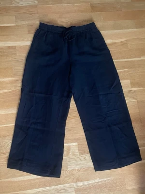 Svarta linnebyxor med resårmidja - Svarta linnebyxor med vida ben och avslappnad passform. Byxorna har snörning i midjan. Tillverkade i ett lätt och luftigt linnematerial som ger en chill och stilren look.