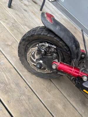 Elsparkcykel med stötdämpare och skivbroms - Säljer en elsparkcykel med grova svarta däck, skivbromsar både fram och bak samt stötdämpare. Cykeln har svarta och röda detaljer, robust ram i metall och plastskärmar. Perfekt för dig som vill ha en stabil och kraftfull elscooter.