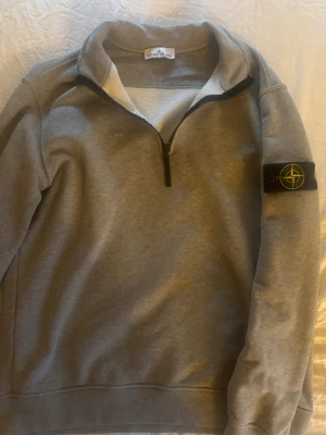 Stone Island half zip - Säljer en Stone Island half zip då den inte används. Den är i färgen grå finns en liten skråma som jag själv inte tycket syns mycket när den använd annars i fint skick