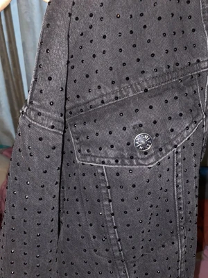 Svart jeansjacka med nitar från Amisu - Cool svart jeansjacka från Amisu med små svarta nitar över hela jackan. Klassisk modell med bröstficka och knappdetaljer. Perfekt för dig som vill sticka ut med en edgy stil och gillar detaljer som syns.