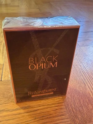 Yves Saint Laurent Black Opium parfym - Black Opium Eau de Parfum från Yves Saint Laurent i en elegant svart och kopparfärgad förpackning. Doften är känd för sin djupa, sensuella karaktär och passar dig som gillar lyxiga och moderna parfymer. Flaskan är rektangulär och materialet är glas.