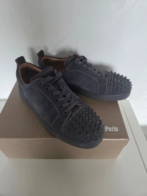 Christian Louboutin - Tjs säljer ett par mörkgrå Christian Louboutin med nitar skorna är i fin skicka och man får med dustbag och extra nitar och hör av er om ni undrar något kan även skicka med en mocka borste