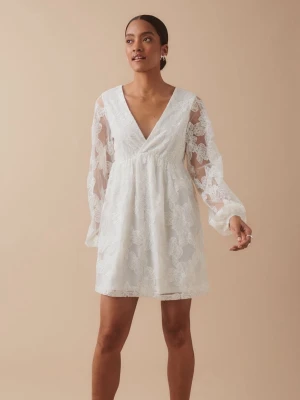 Blommig studentklänning - Superfin vit kortklänning med v-ringning och långa ärmar i mesh! Suuupersnygg på utspringet :) Aldrig använd. Skickas direkt!
