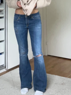 Lågmidjade utsvängda jeans - Supersnygga lågmidjade utsvängda jeans med hål i mycket bra skick! Måtten finns bland bilderna och färger syns bäst på sista bilden. Pris kan diskuteras🥰