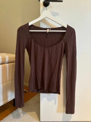 Nelly tröja  - En enkel och stilren brun långärmad topp med rundad halsringning. Perfekt att matcha med jeans eller kjol för en avslappnad look. Tunn och mjuk i materialet, sitter skönt mot kroppen.