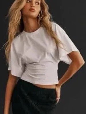 Nelly tröja  - Trendig vit croppad t-shirt med rund halsringning och vida korta ärmar. Perfekt för en avslappnad och stilren look. Tillverkad i mjukt bomullsmaterial som känns skönt mot huden. Dock en liten fläck som inte syns så mkt där fram