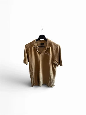 Grön Peak Performance polotopp - Säljer en grön polotopp från Peak Performance med klassisk krage och korta ärmar. Toppen har diskret logotyp på bröstet och är tillverkad i mjuk bomull, perfekt för en avslappnad och stilren look.