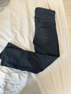 Svarta raka jeans från H&M - Säljer ett par mörkblå raka jeans från H&M med klassisk femficksmodell och signaturdetalj på bakfickan. Jeansen har en snygg tvättad look och är tillverkade i slitstark denim. Perfekta för en avslappnad och stilren outfit.