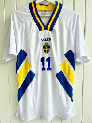 Tomas Brolin - Sverige - VM 1994 - Säljer en klassiska fotbollströja, Tomas Brolins svenska vita bortamatchtröja från VM 1994 i USA. Tröjan är en reprint i nyskick.  Aldrig använd.    Storlek: Large
