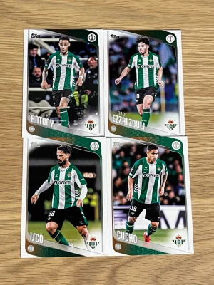 Fotbollssamlarbilder Real Betis - Fyra samlarkort med spelare från Real Betis: Antony, Abde Ezzalzouli, Isco och Cucho. Kortens design har gröna och vita färger med klubbens logga och spelarnas namn. Materialet är glansigt papper och korten har detaljerad information om spelarna på baksidan.