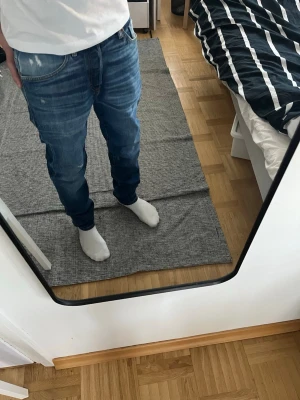 Diesel jeans - Säljer ett par blå jeans med snygga slitningar och tvättade detaljer. Jeansen har klassisk femficksdesign och raka ben. Materialet är denim och färgen är mörkblå med ljusare partier. Perfekt för dig som gillar en avslappnad och trendig look.