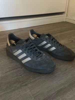 Adidas Spezial grå sneakers - Snygga Adidas Spezial sneakers i grå mocka med vita detaljer och klassiska tre ränder på sidan. Låg modell med mörkgrå snörning och vit hälflik. Perfekta för en sommar eller vårdag. De är storlek 42 och är köpta på JD och inte använts särskilt mycket. Hör av dig vid frågor eller vill se bilder 
