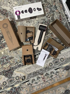 Dyson Supersonic hårfön svart/lila - Säljer en Dyson Supersonic hårfön i svart med lila detaljer. Medföljer flera munstycken och originalkartong samt manual. Sladden är lång och robust, och allt är snyggt förpackat i bruna kartonger. Perfekt för dig som vill ha en kraftfull och modern hårfön.