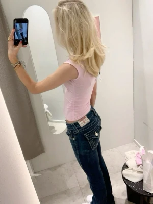 Mörkblå true religion jeans joey low rise flare - Säljer ett par mörkblå jeans från True Religion med klassiska kontrastsömmar och detaljerade bakfickor med lock och knappar. Jeansen har låg midja och raka ben. Materialet är denim i bomull med en snygg tvätt och logopatch bak.