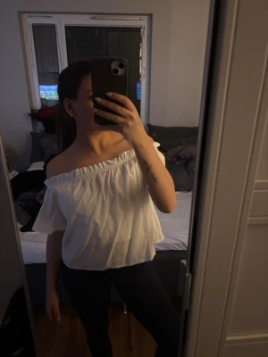 offshoulder topp - Säljer en söt vit offshoulder topp med volangkant, som tyvärr inte kommer till användning längre då den blivit för liten för mig. Toppen är axelbandslös och har en luftig passform som ger en avslappnad och trendig look. Perfekt att matcha med jeans eller kjol för en fräsch stil till sommaren. 🌻☺️