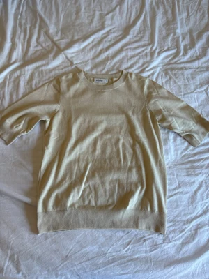 Beige stickad tröja  - Snygg beige stickad tröja  med rund halsringning och halvlånga ärmar. Tröjan har ribbade muddar vid ärmslut och nederkant. Perfekt basplagg i mjukt material som passar till det mesta.