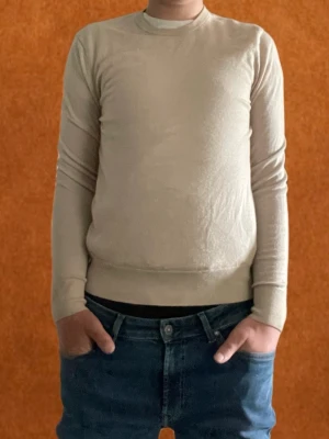 Beige stickad tröja från Uniqlo - Säljer en stilren beige stickad tröja från Uniqlo med rund hals och långa ärmar. Tröjan har ribbstickade muddar vid ärmslut och nederkant, vilket ger en snygg passform. Perfeckt till en grich outfit  och enkel att matcha med jeans. Mitt pris 250 skriv vid funderingar 🍾🍾😎😎🔥🔥