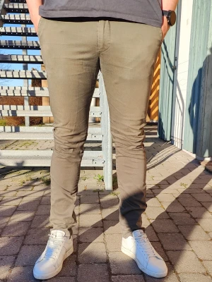 Slim fit gröna chinos, John Henric W32 - Olivgröna chinos från John Henric i slim fit. Smal passform med lite stretch i tyget, så de är bekväma att ha på sig. • Storlek: W32 • Färg: Olivgrön • Passform: Slim fit • Material: Bomull med stretch • Skick: Bra använt skick