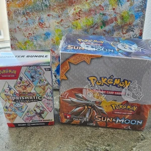 Pokémon Sun & Moon och Prismatic Evolutions - Säljer två Pokémon Trading Card Game boxar: en Sun & Moon booster box och en Prismatic Evolutions booster bundle. Båda boxarna är oöppnade och innehåller flera booster packs med samlarkort. Perfekt för dig som vill utöka din samling eller spela med vänner. Det är ej original därför säljs som billigt!