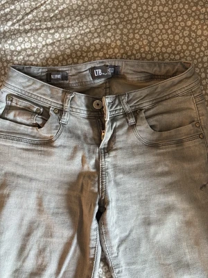 Grå jeans från LTB Alerie - Snygga grå jeans från LTB, modell Alerie. De har klassisk femficksdesign, utsvängda ben och coola detaljer vid fickorna. Materialet är mjukt och stretchigt för en bekväm passform. Perfekt för dig som gillar en stilren look. 💘