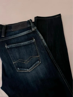 Mörkblå Replay anbass jeans slim fit - Säljer ett par mörkblå slim fit jeans från Replay med snygga slitningar och kontrastsömmar. Klassisk femficksmodell med dragkedja och knapp. Perfekta för dig som gillar en smalare passform och vill ha ett par stilrena jeans i denim. Pris går att diskutera 👍