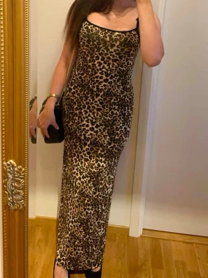 Leopardmönstrad långklänning Nelly - Säljer en långklänning från Nelly med leopardmönster. Klänningen har smala axelband och är figurnära med en rak siluett. Färgerna går i beige, svart och brunt. Perfekt för dig som vill sticka ut med ett djurmönstrat plagg.